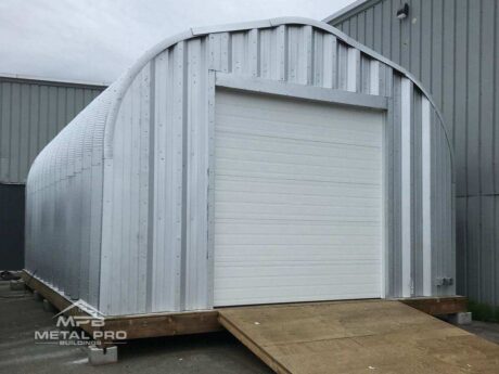 quonset hut steel shed building with white garage door opening