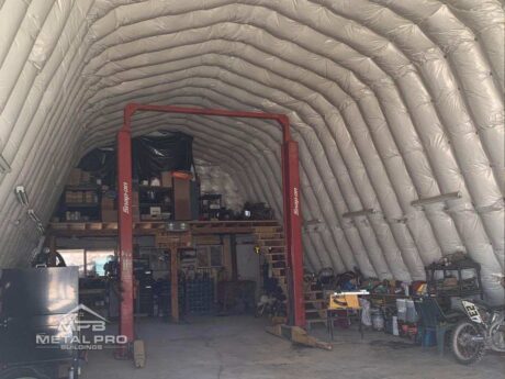 interior of a quonset hut storage building with a hoist for vehicles