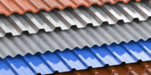 Stacked sheets of corrugated metal roofing in red, silver, and blue colors.