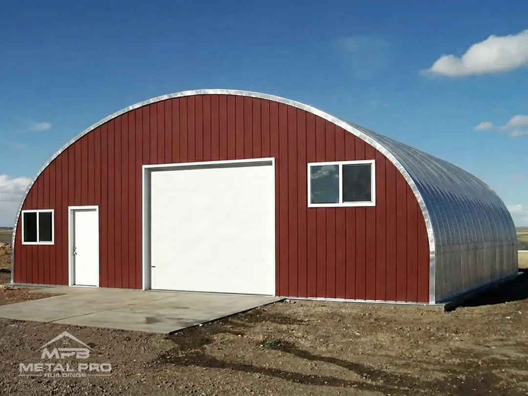 Red metal arch building featuring white garage and entry doors and two windows.