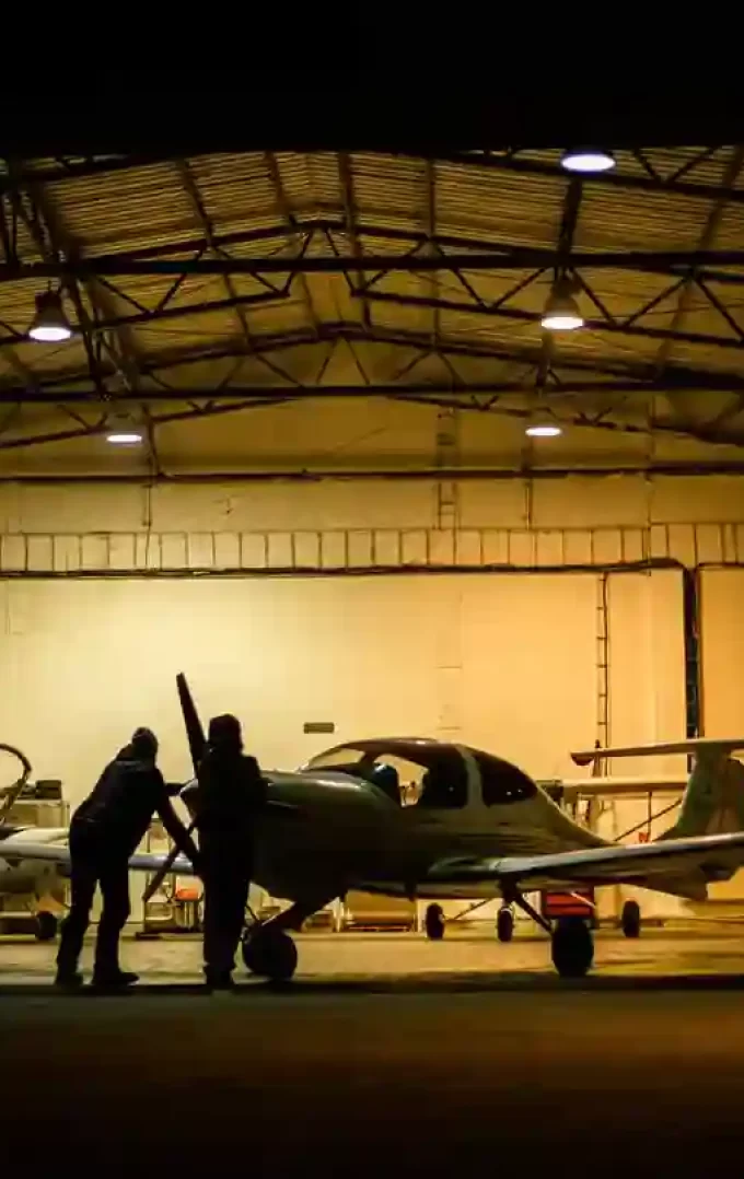 two individuals parking a plane in an aircraft hangar